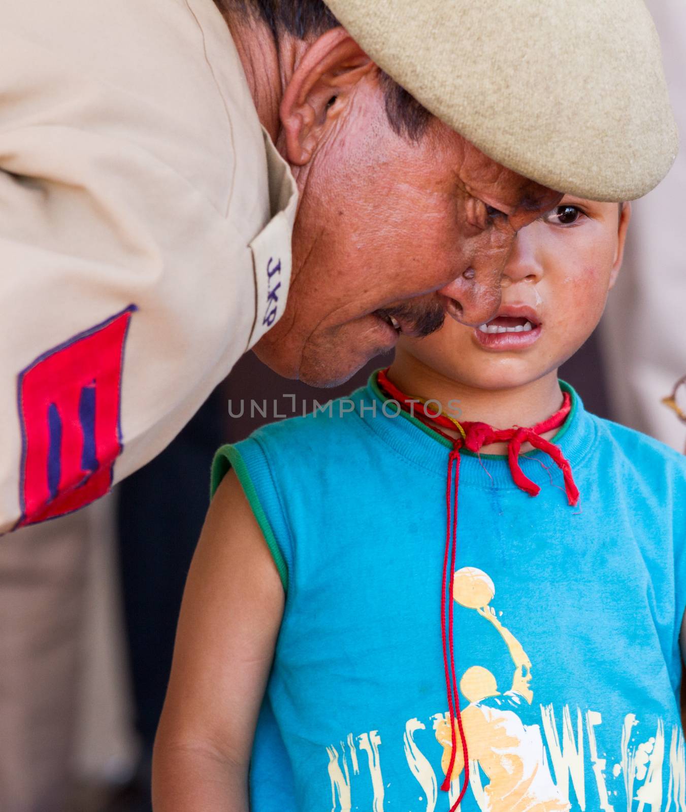 Leh, India - August 7, 2012: Military man comforting a crying baby boy at the His Holiness the 14th Dalai Lama teachings in Leh, Ladakh, Jammu and Kashmir, India