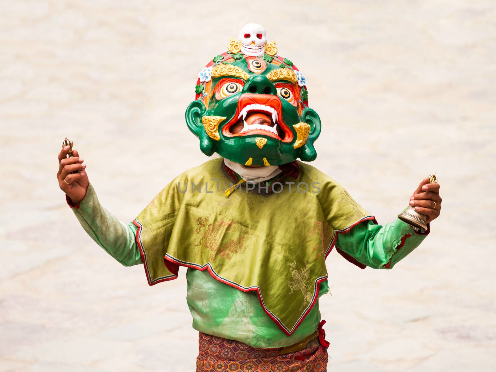 Monk with ritual bell and vajra performs a religious masked and costumed mystery dance of Tibetan Buddhism during the Cham Dance Festival by straannick