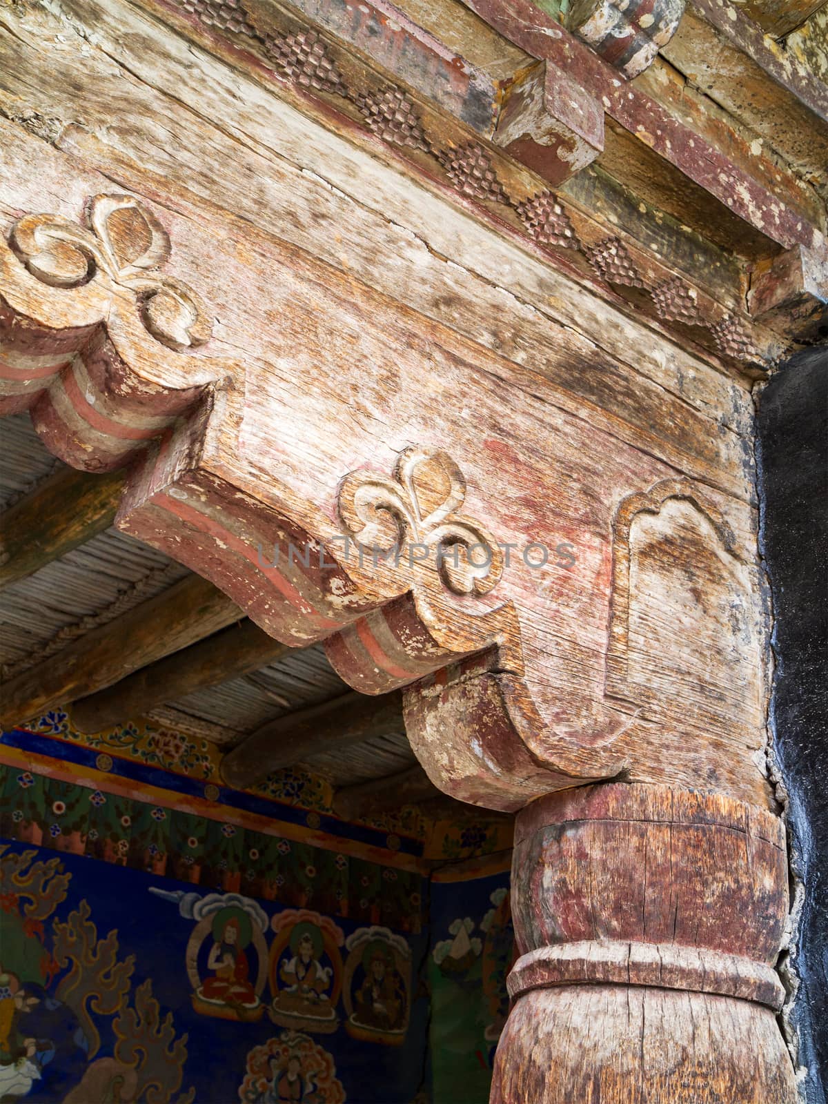 Old, cracked wooden columns of the ancient Buddhist temple, decorated with beautiful antique ornaments (Ladakh, northern India)