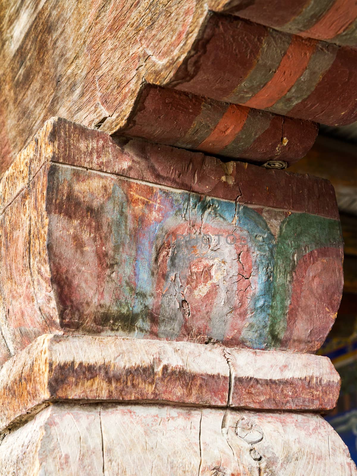 Old, cracked wooden columns of the ancient Buddhist temple, decorated with beautiful antique ornaments (Ladakh, northern India)