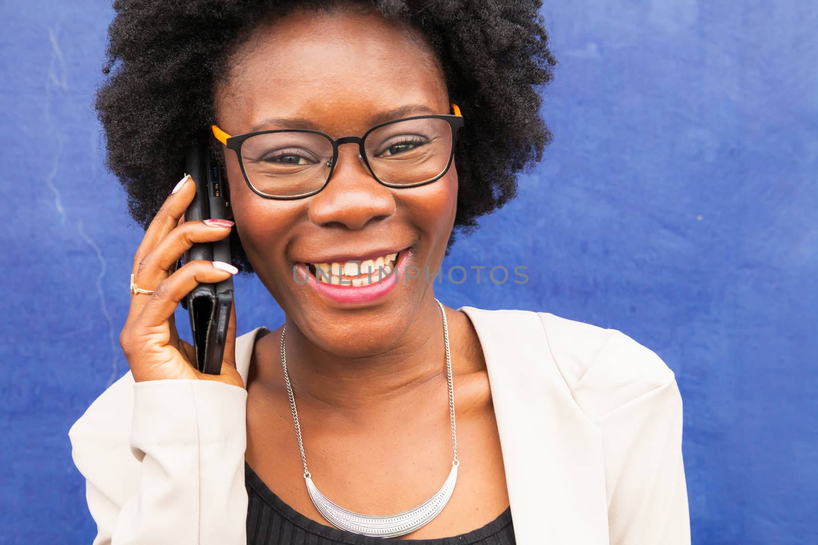 Black woman talking on phone standing on a blue background