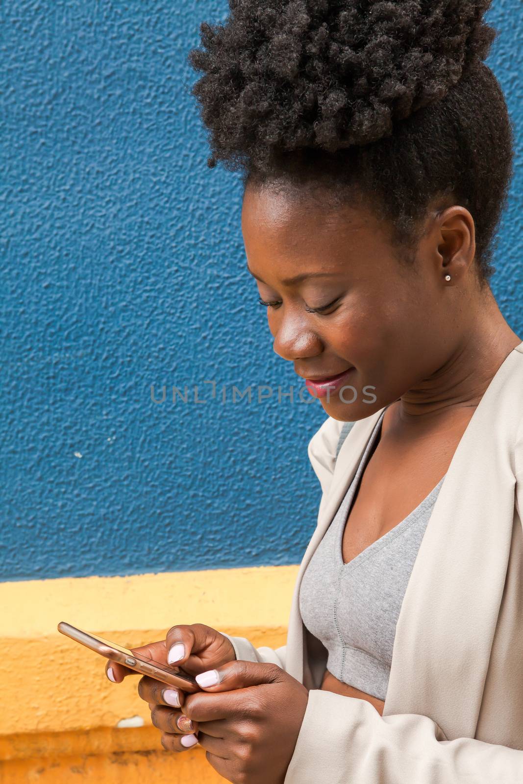 Young african woman chatting with her smartphone by andongob