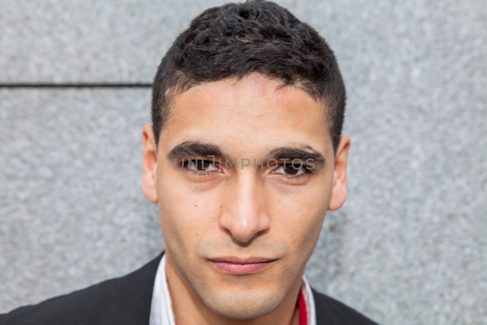 Young elegant arab man thinking next to a stone wall