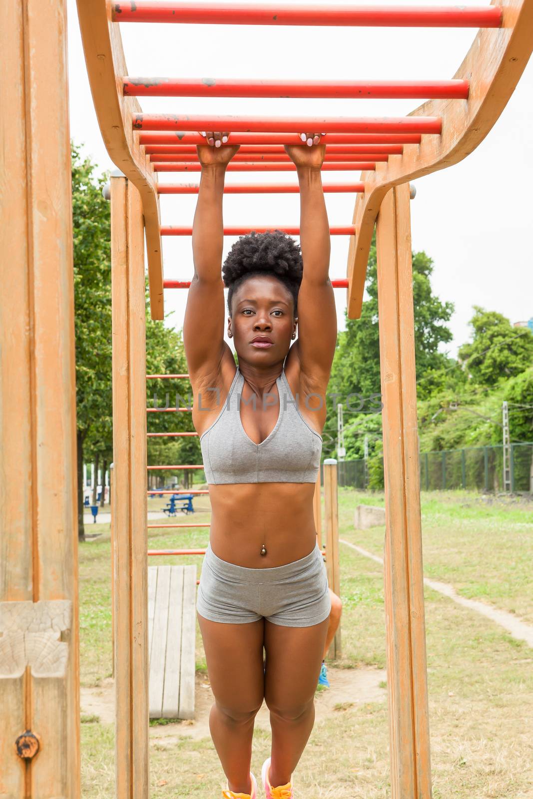 African young woman doing stretching exercises in urban structures for sports in a city park