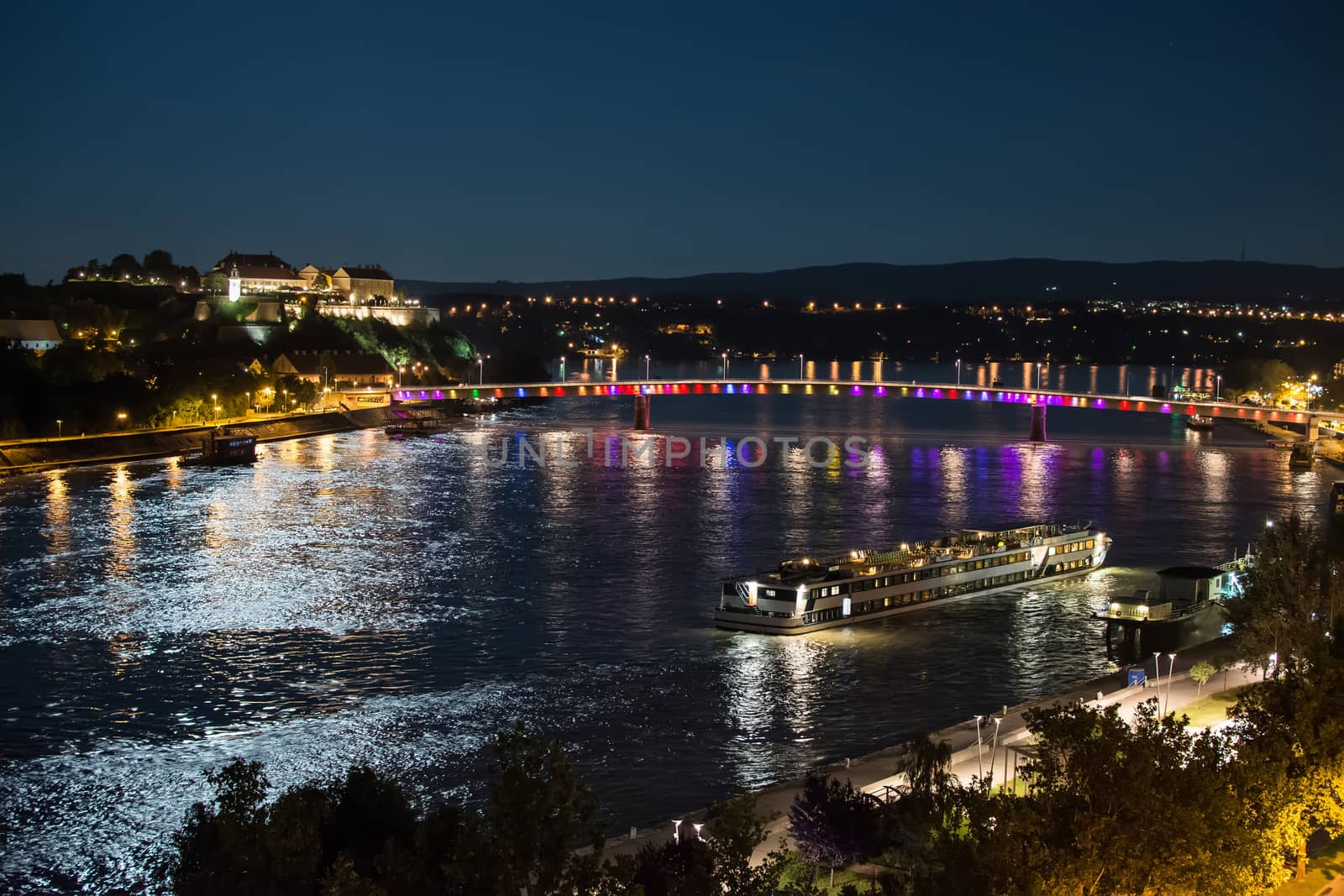 Petrovaradin Fortress and "Rainbow bridge" Over the Danube, Between Novi Sad and Petrovaradin in the Moonlight With Ship Docking by Victority