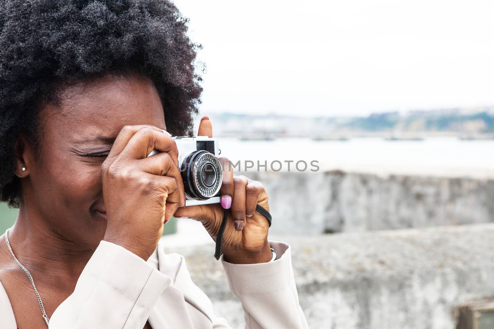 Modern African woman shooting with her vintage camera outdoors in a cloudy day