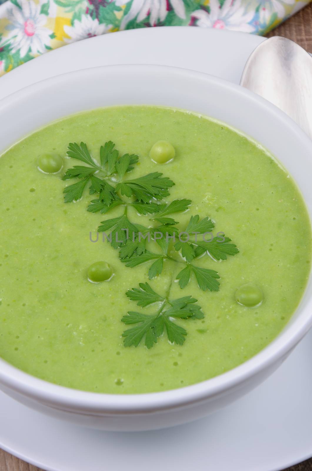 A plate of soup puree of green peas with parsley on a table