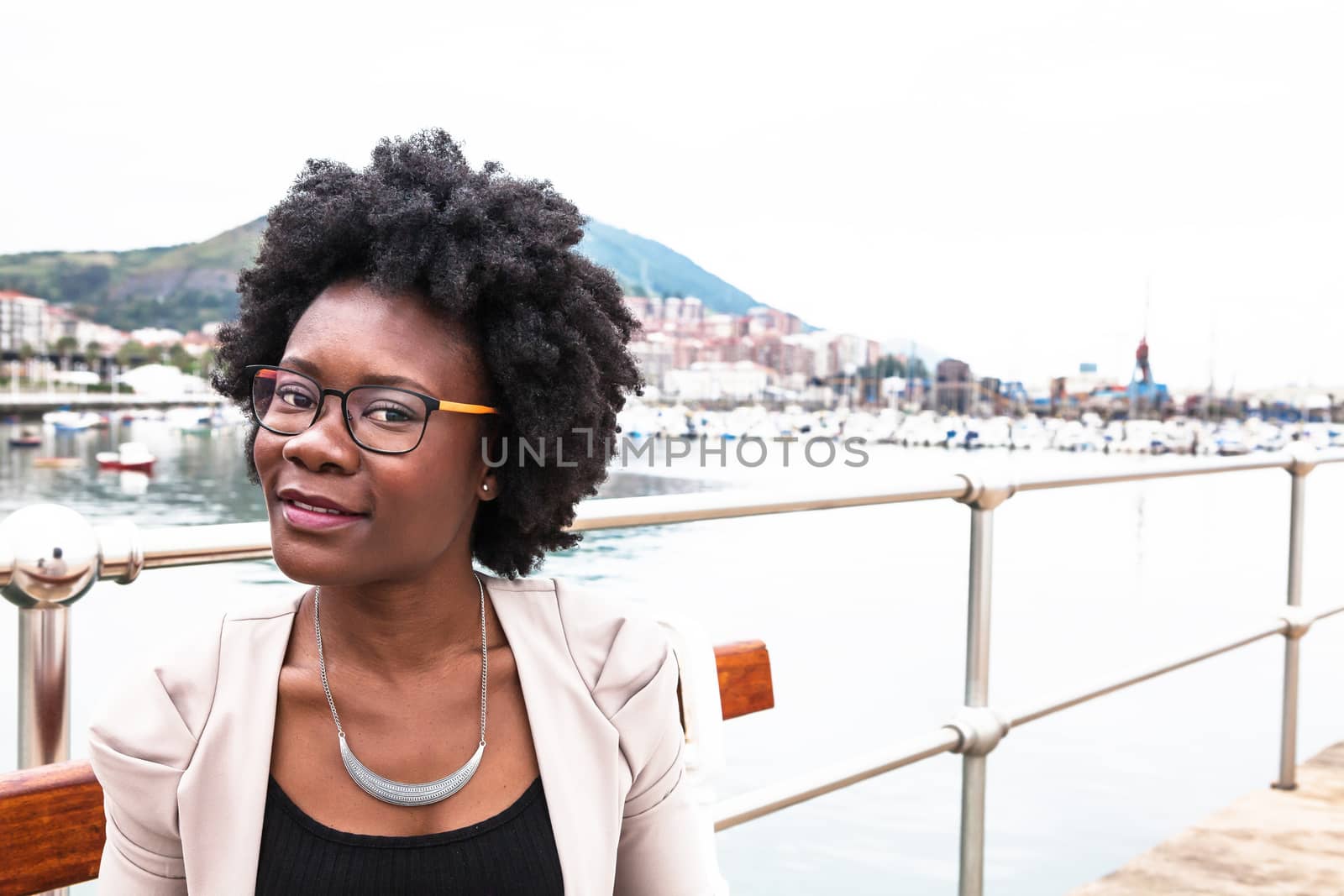 Young african woman looking to the camera near a seaport in a cloudy day