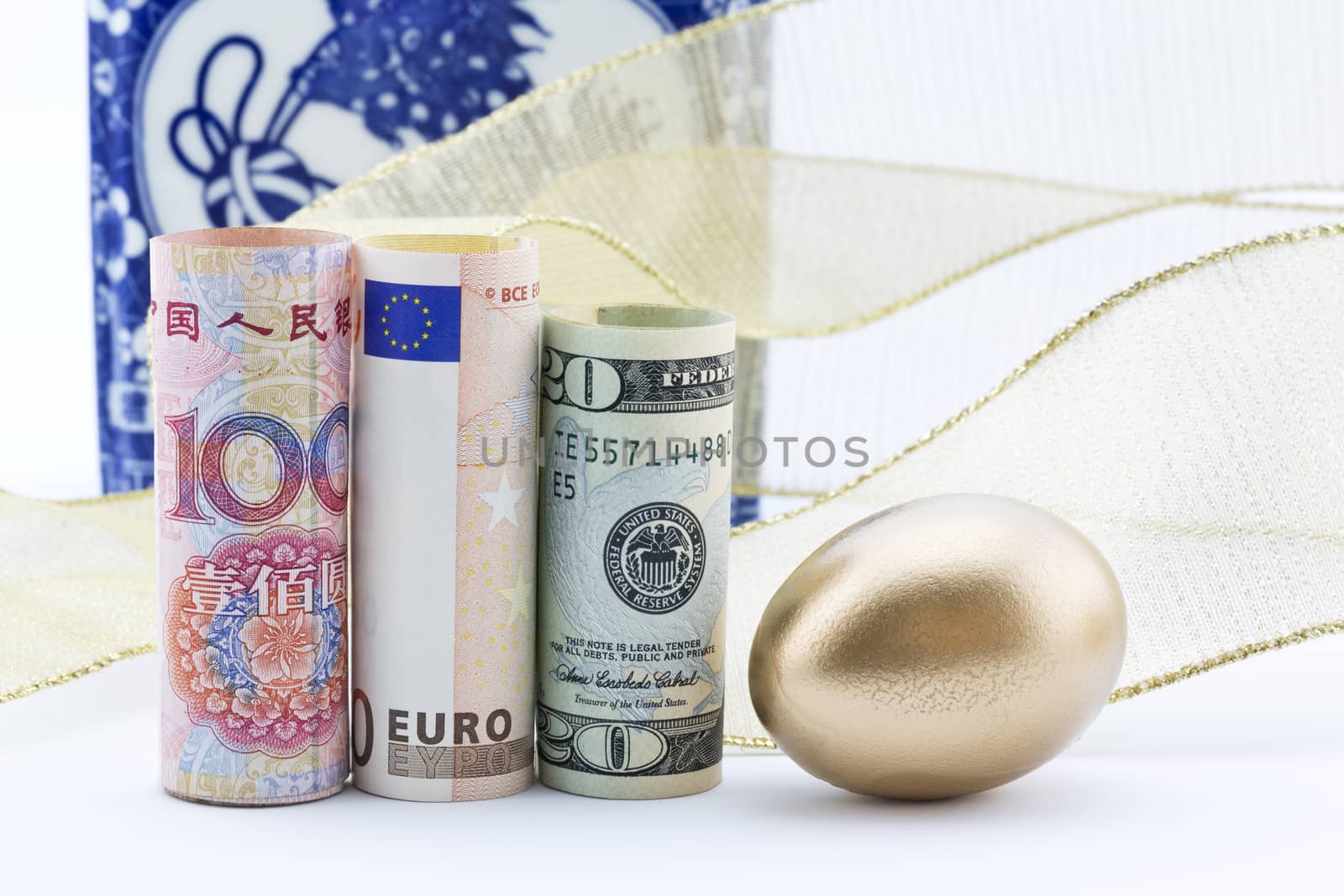 Chinese yuan surrounded by gold ribbon and egg with euro and American currency reflect global business success. 