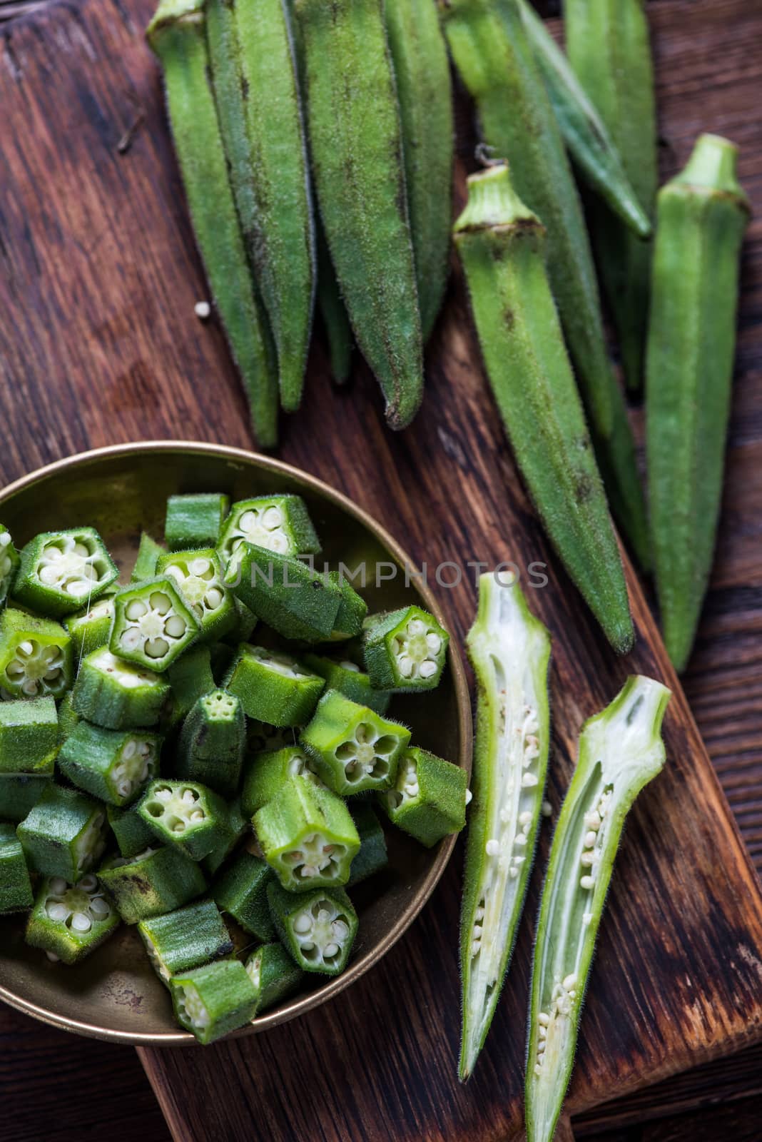 Farm fresh okra on wooden board, whole and sliced