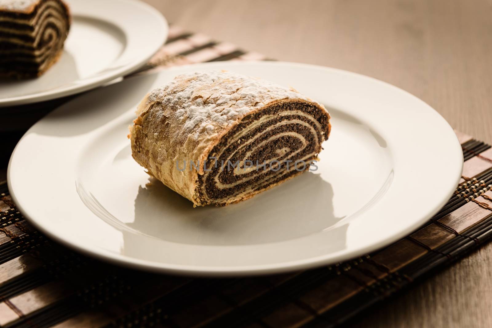 strudel with poppy seeds on a ceramic white plate on wooden background