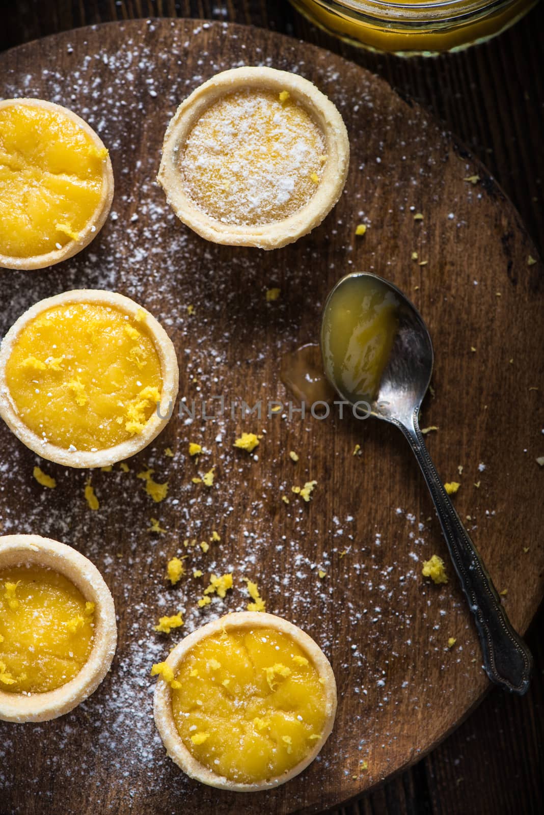 filling lemon and custard mini tarts on wooden rustic board on kitchen table