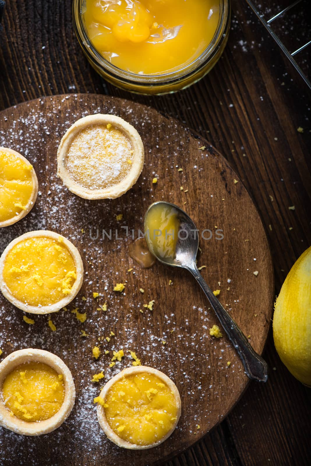 filling lemon and custard mini tarts on wooden rustic board on kitchen table