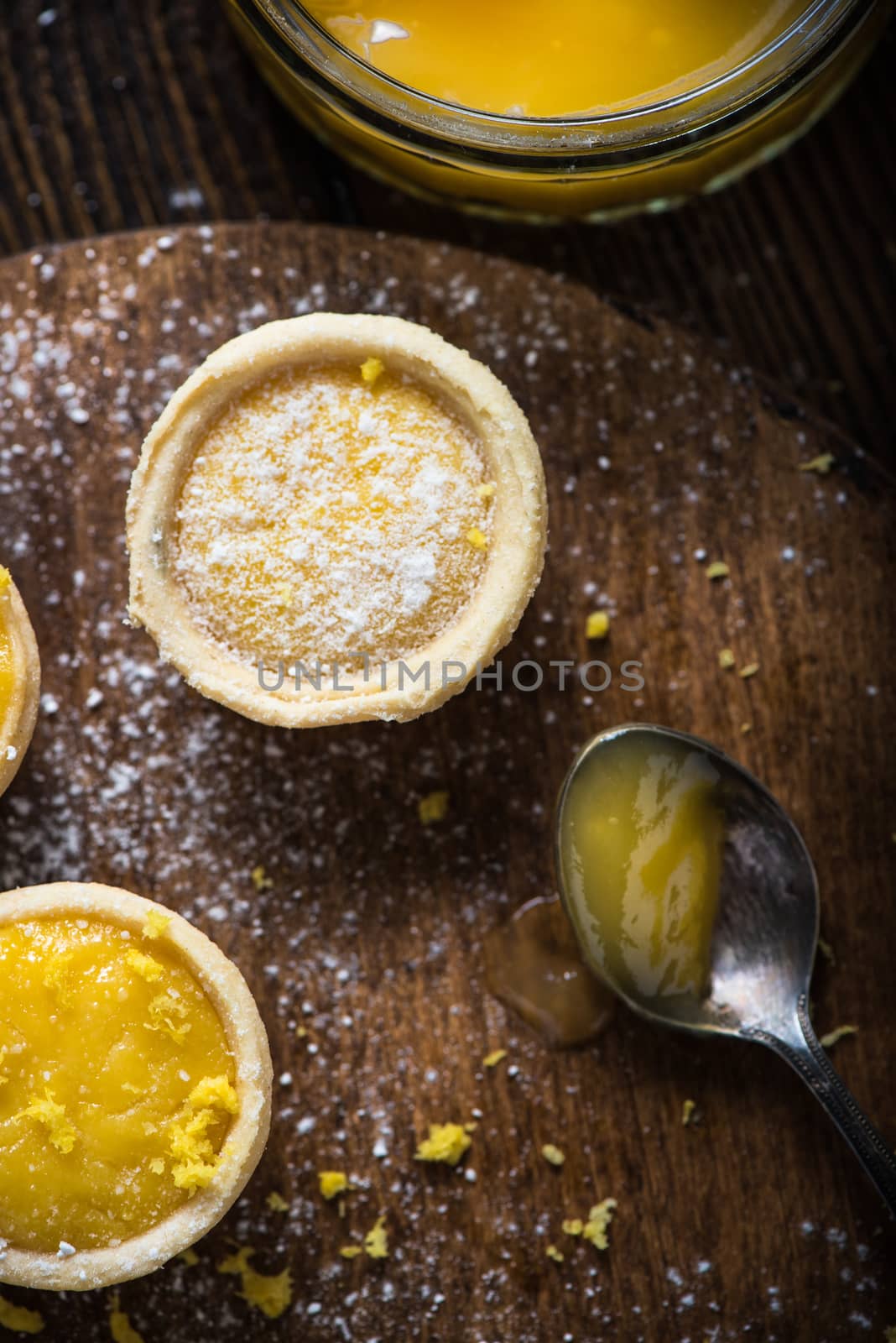 filling lemon and custard mini tarts on wooden rustic board on kitchen table