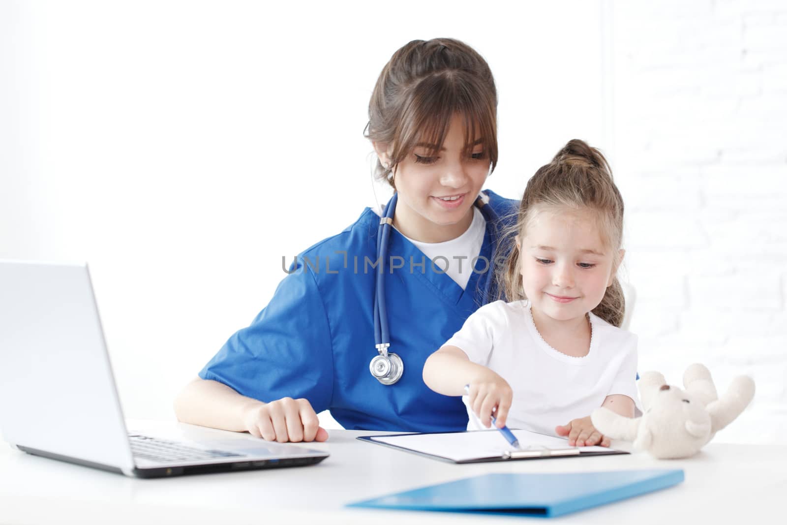 Child patient and young female doctor writing diagnosis