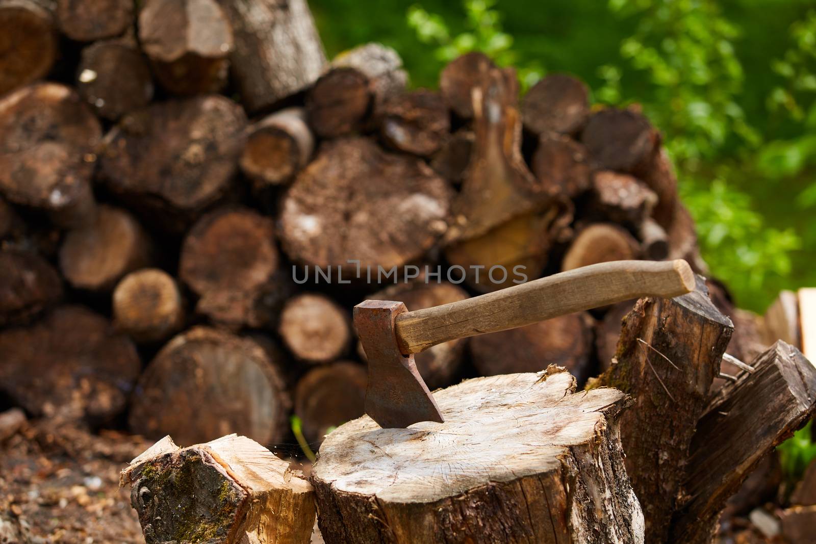 Old ax on a log and firewood in the background