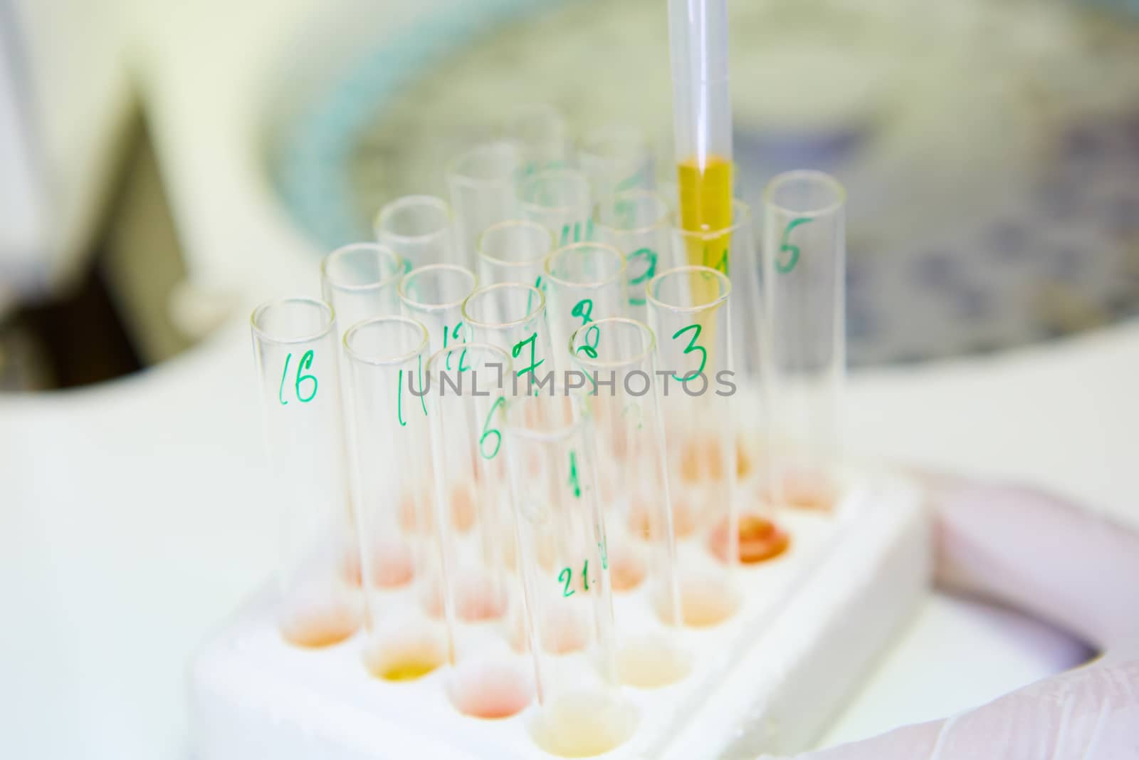 A pipette dropping sample into a test tube,abstract science background. Shallow dof