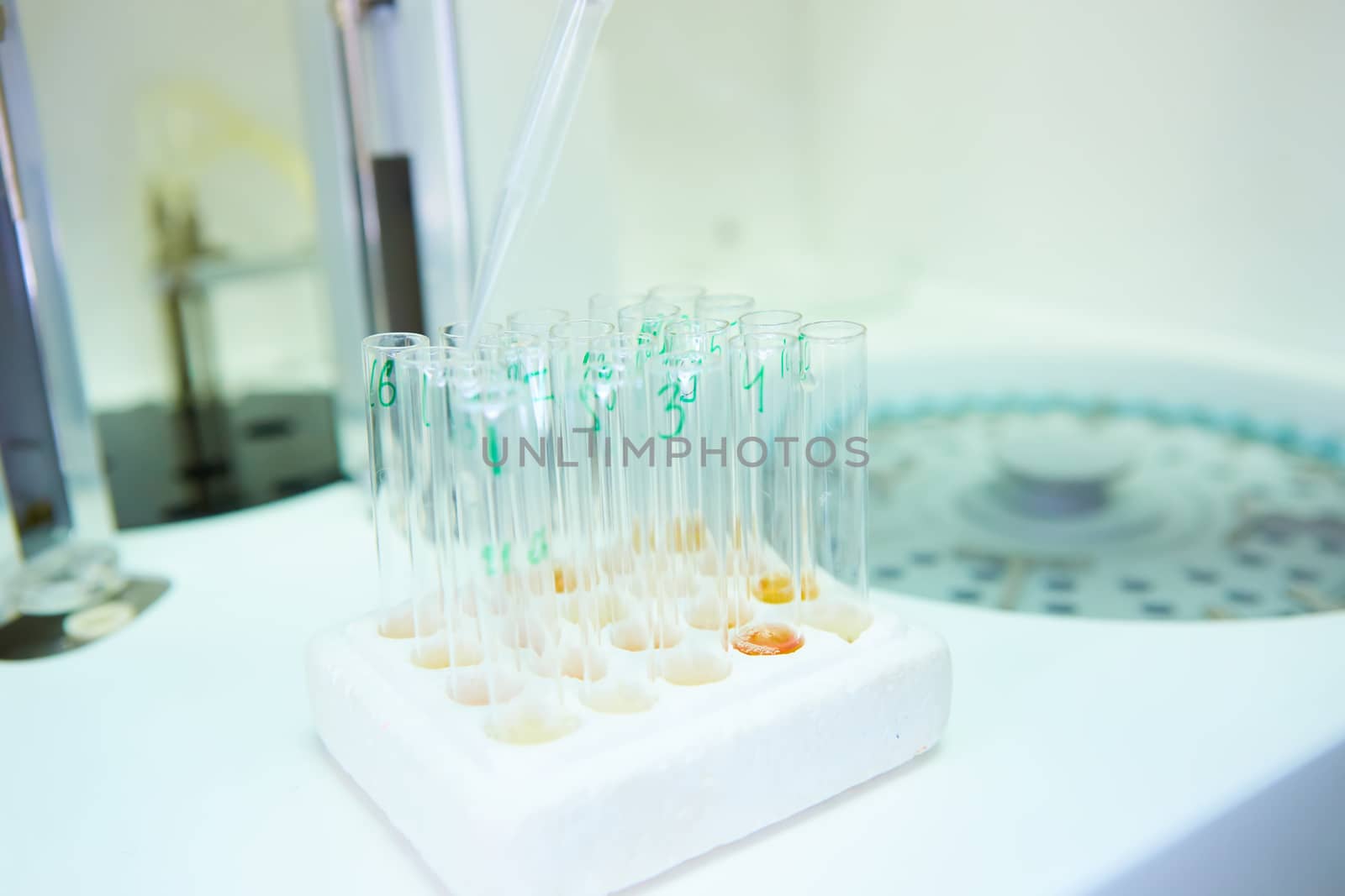 A pipette dropping sample into a test tube,abstract science background. Shallow dof