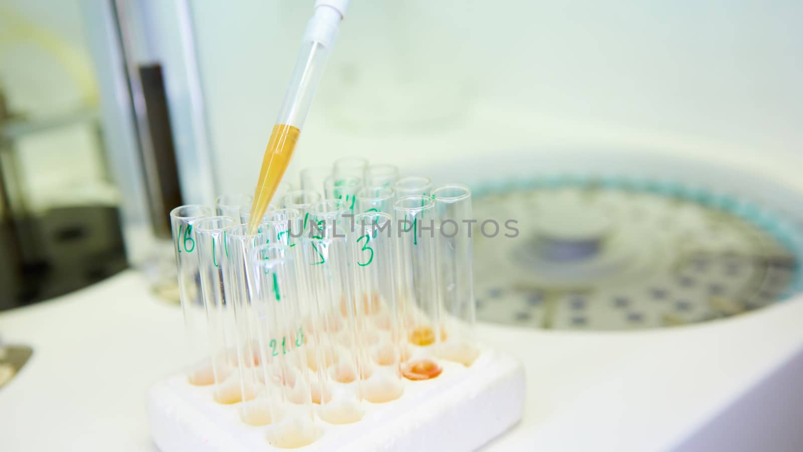 A pipette dropping sample into a test tube,abstract science background. Shallow dof