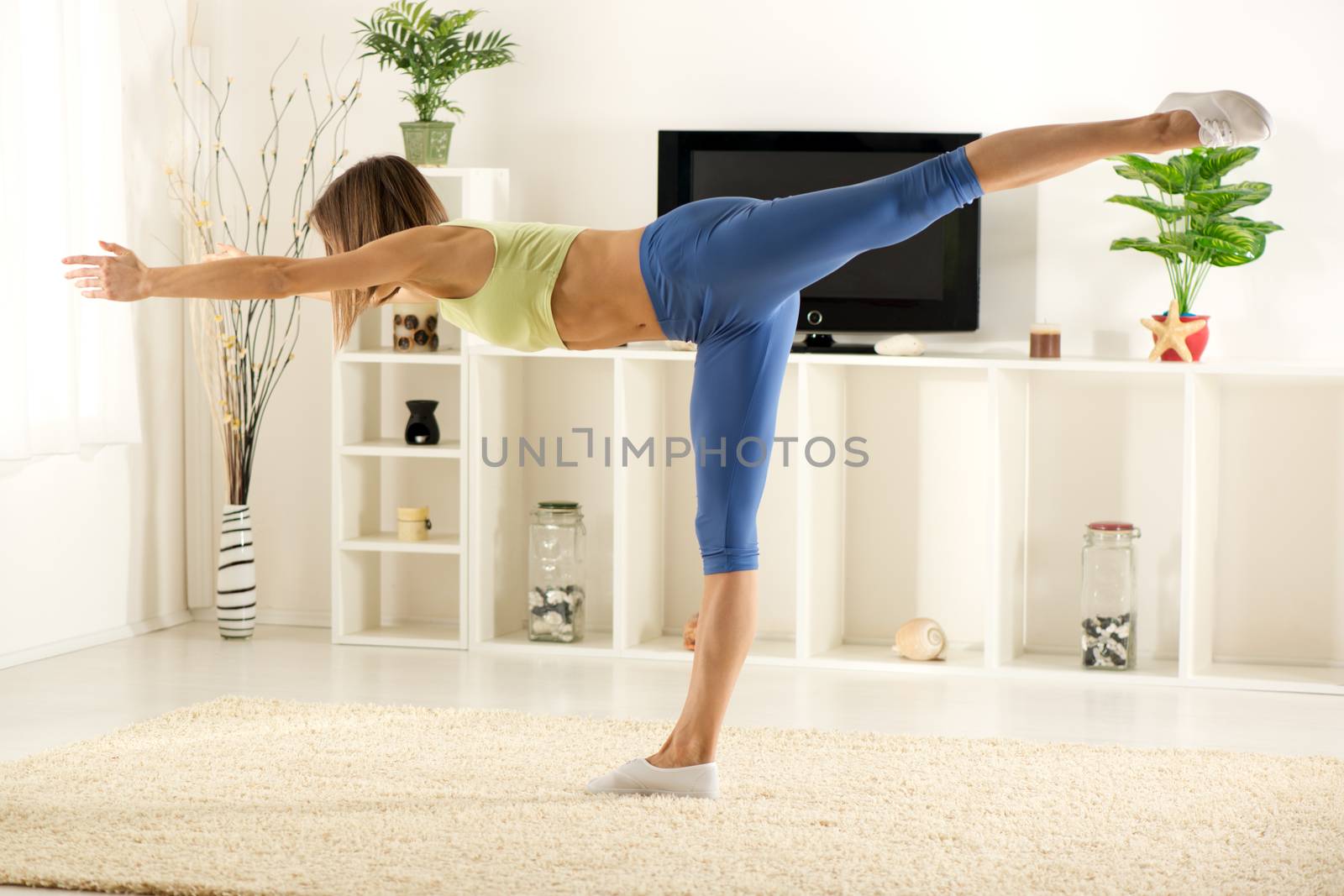 Young woman in sports clothes doing exercises in the room.