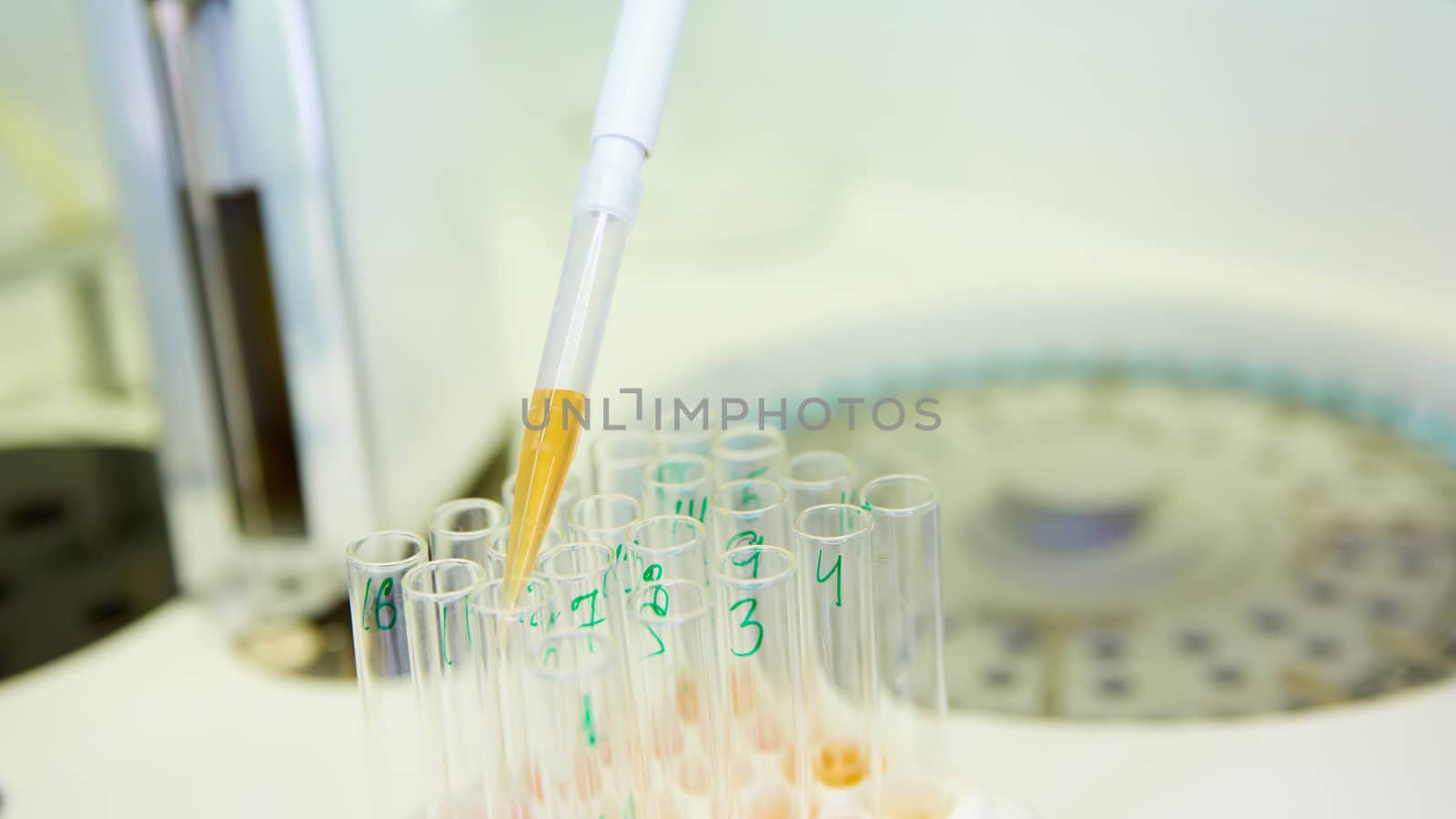 A pipette dropping sample into a test tube,abstract science background. Shallow dof