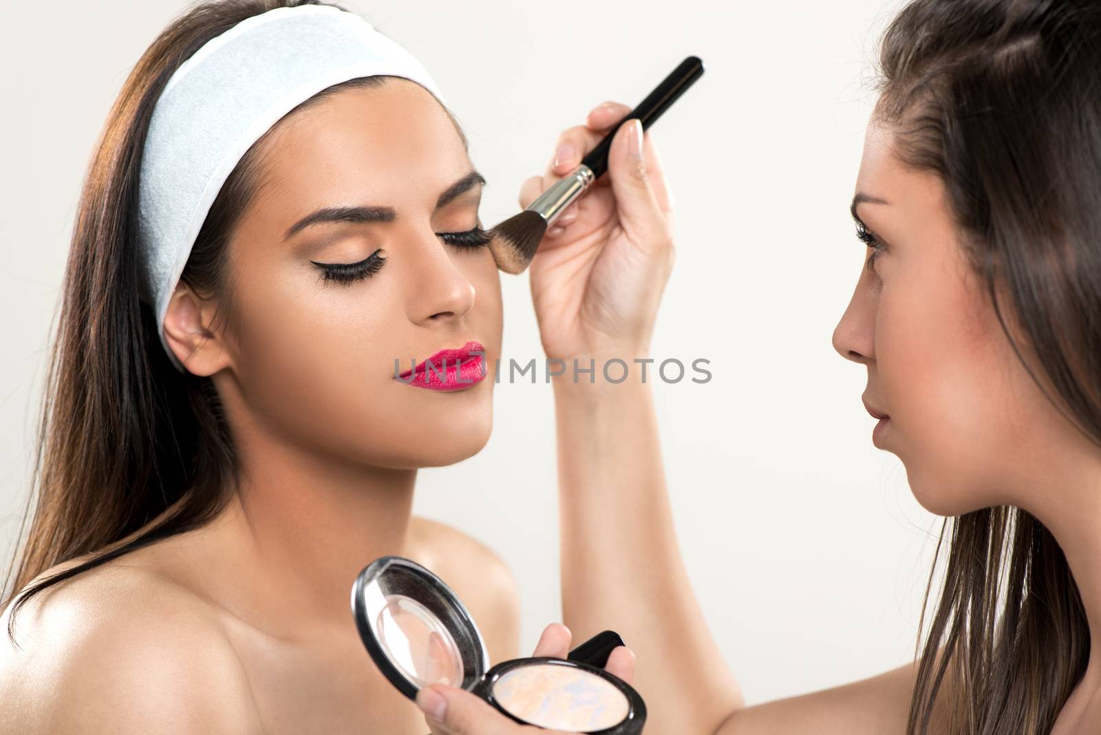 Makeup artist applying powder on a beautiful young woman's face