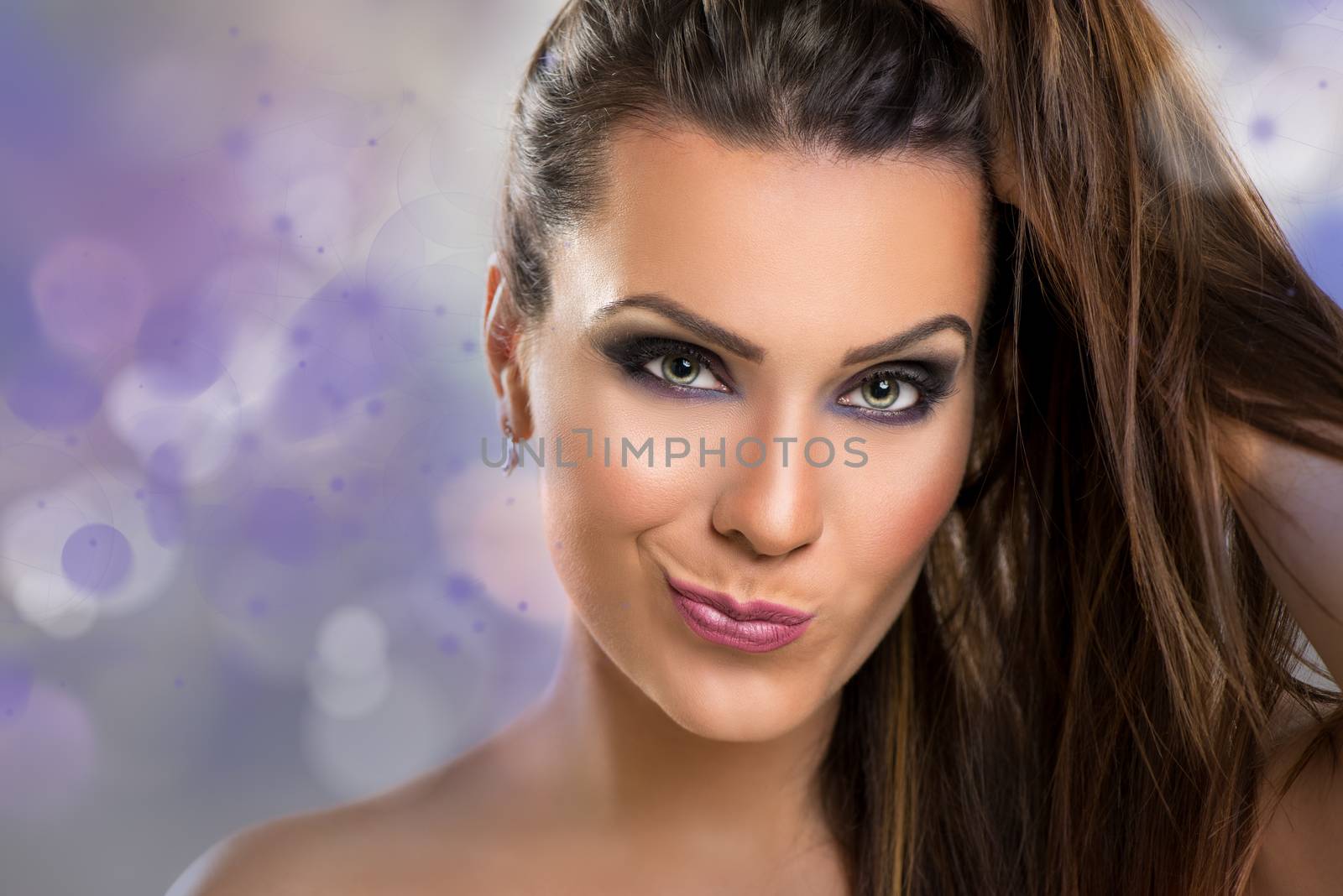 Portrait of a cute young brunette woman making a face with perfect make-up and crazy hair.
