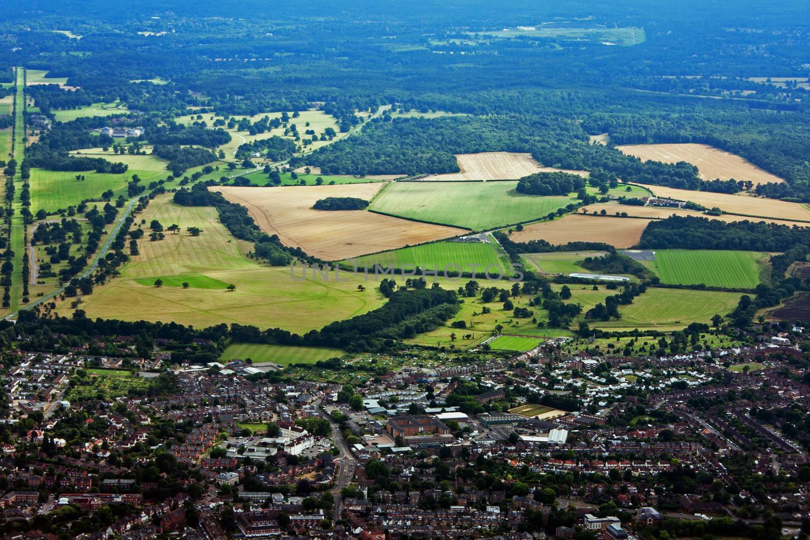 Aerial view of city town surrounded by farmland and forests.