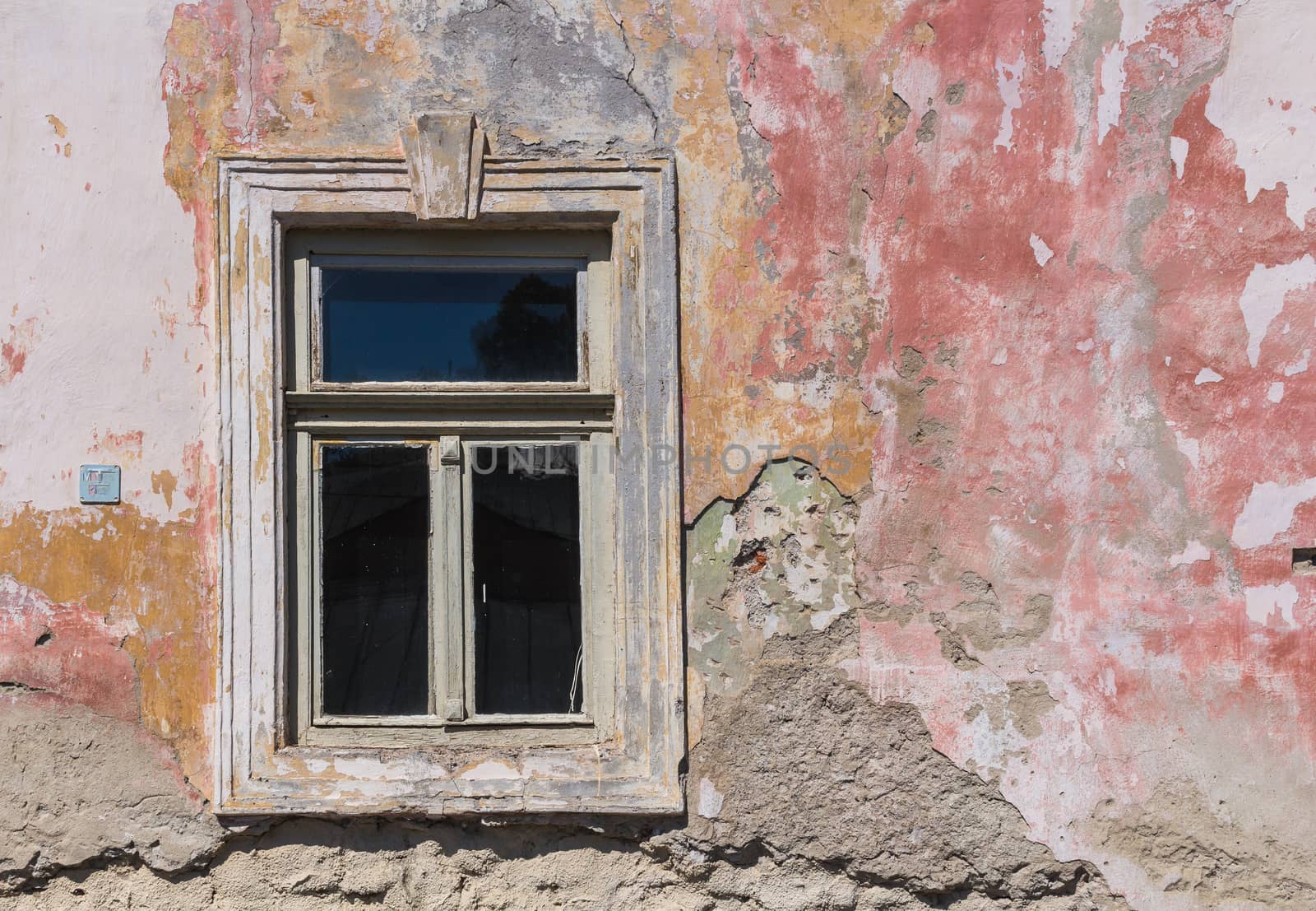 Window of an old abandoned house. Still with glass. Colorful facade created by the layers of various colors used.