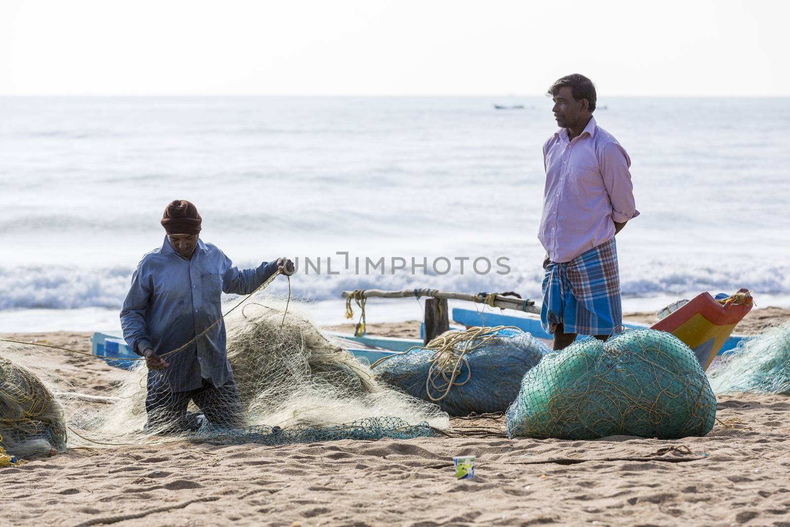 Pondichery, Tamil Nadu, India - February 27, 2014 : Traditional fishermen on beach, on sea, on sand. Long boats, Hard work poor people