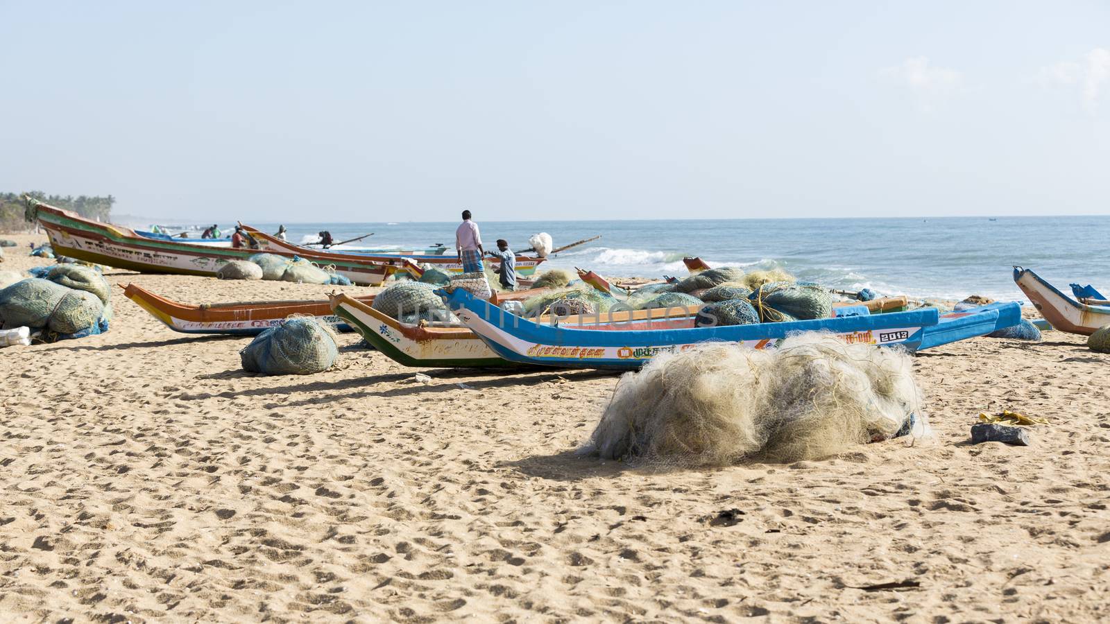 Pondichery, Tamil Nadu, India - February 27, 2014 : Traditional fishermen on beach, on sea, on sand. Long boats, Hard work poor people