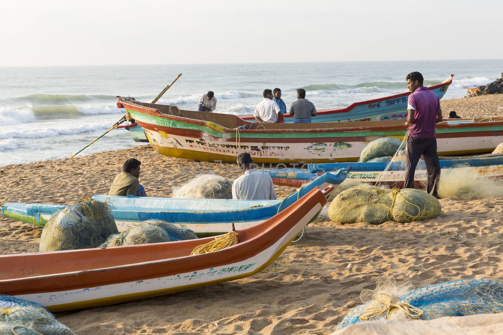 Pondichery, Tamil Nadu, India - February 27, 2014 : Traditional fishermen on beach, on sea, on sand. Long boats, Hard work poor people