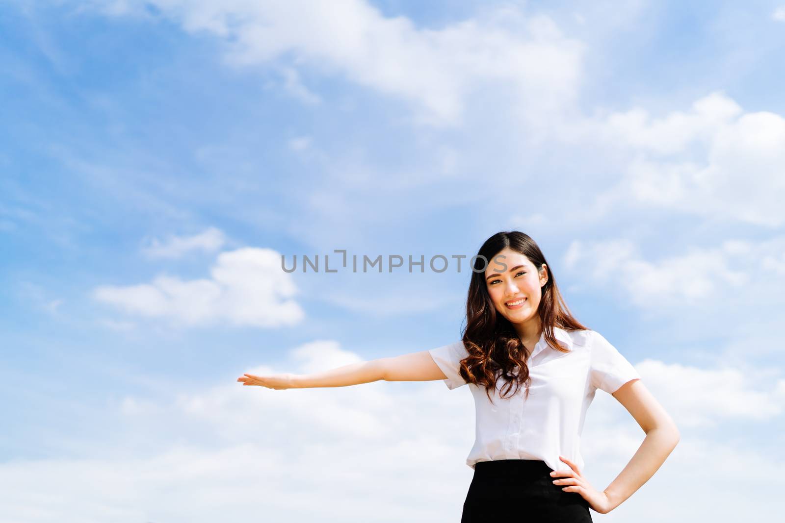 Beautiful young asian university or college student woman doing advertising or product presenting pose, copy space on blue sky background, education or job or advertisement concept by beer5020