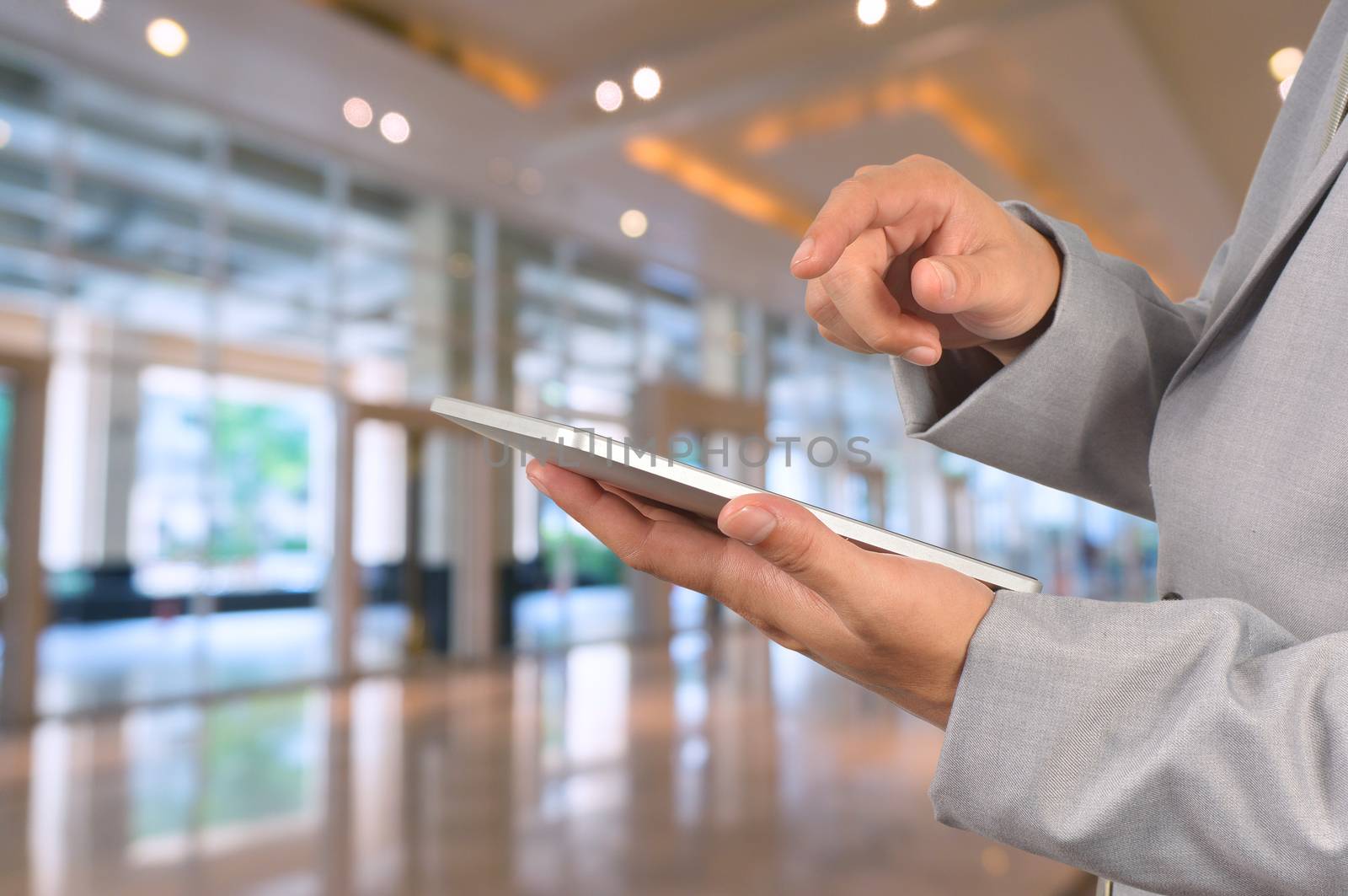 Young Businessman using tablet standing in office, Hotel Lobby or Ballroom