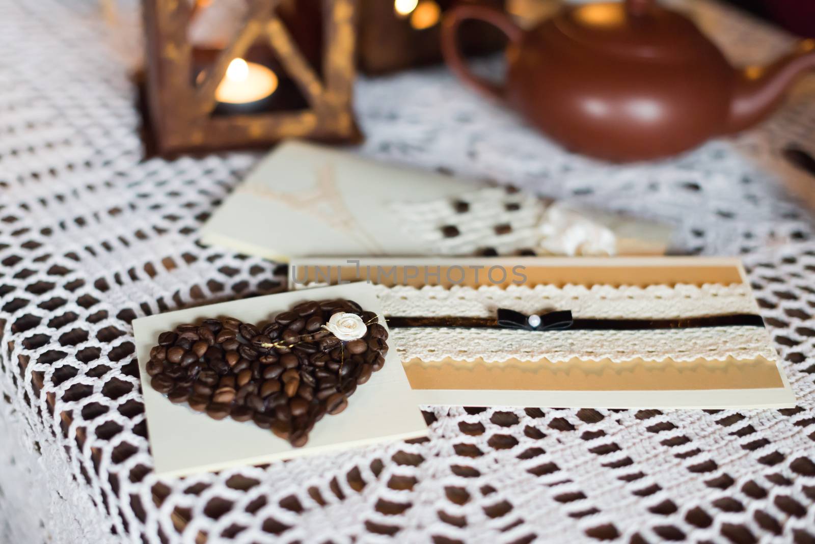 postcard with coffee beans in the shape of a heart is on the white tablecloth