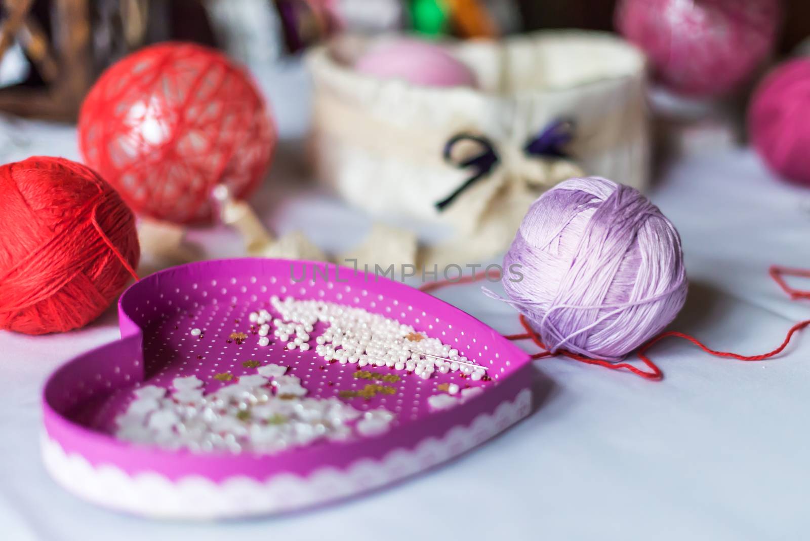 decorations in the shape of heart and balls of yarn are on a white tablecloth