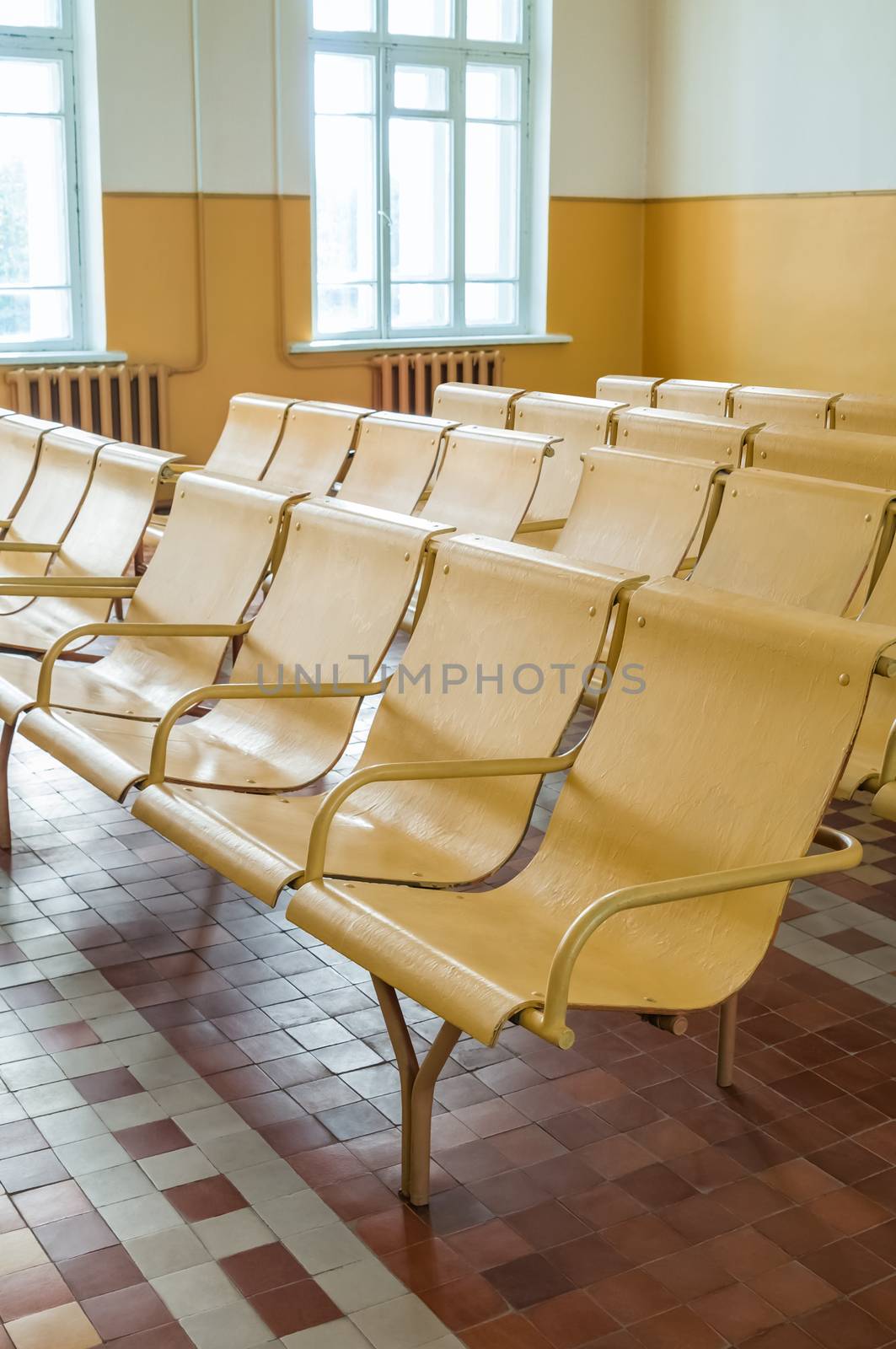 Old railway station waiting room with empty chairs.