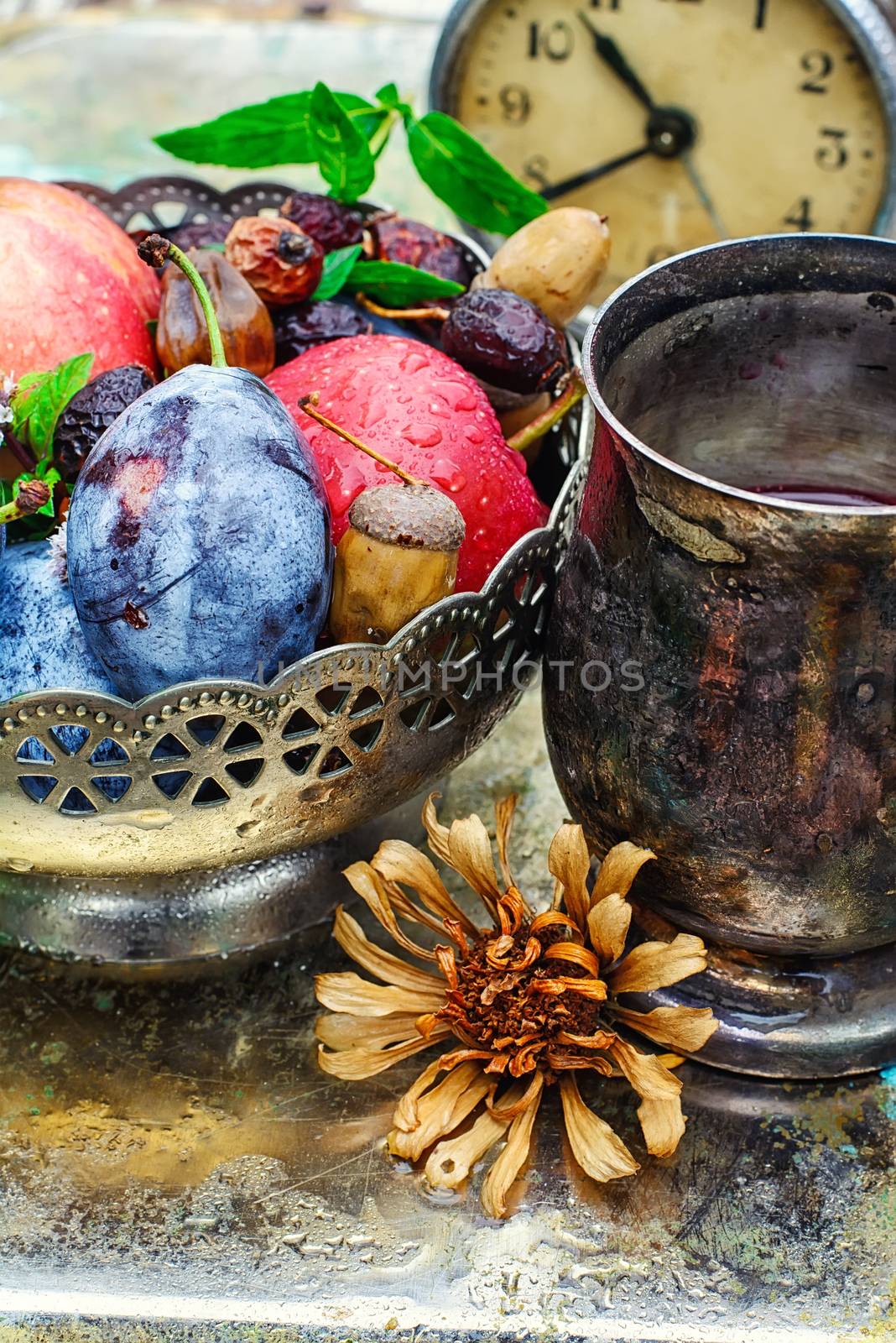 apples with plums on background of tea cups with decoration of pine cones,acorns and chestnuts