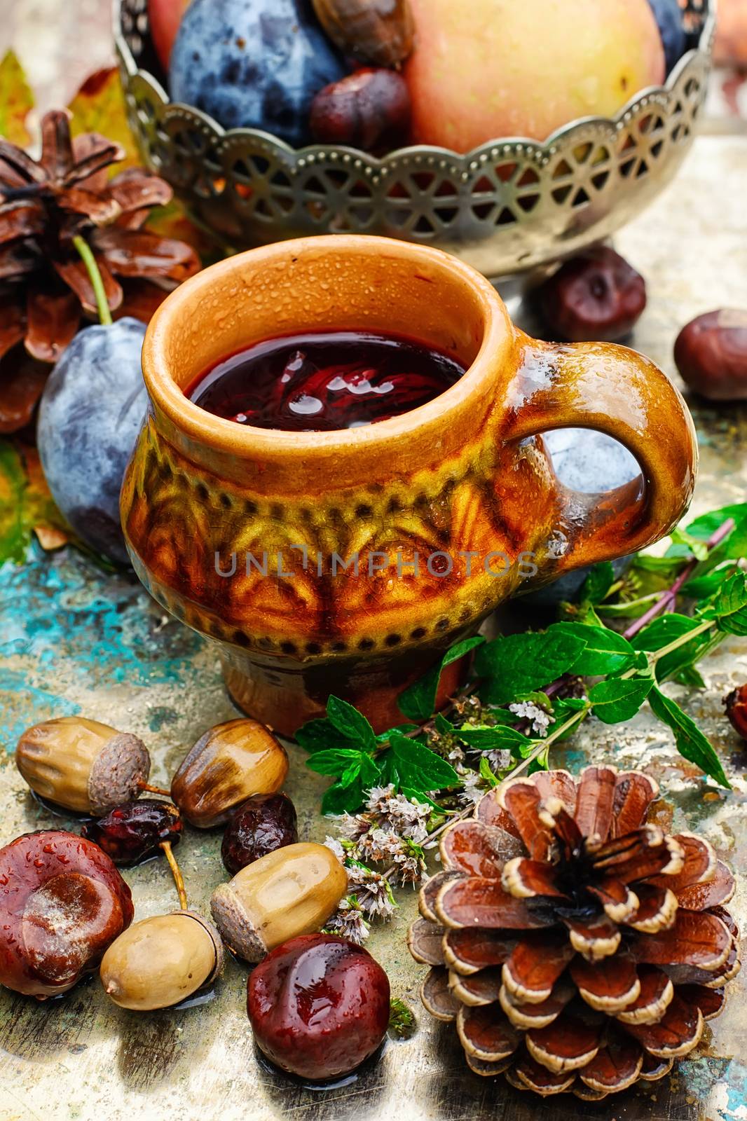 apples with plums on background of tea cups with decoration of pine cones,acorns and chestnuts