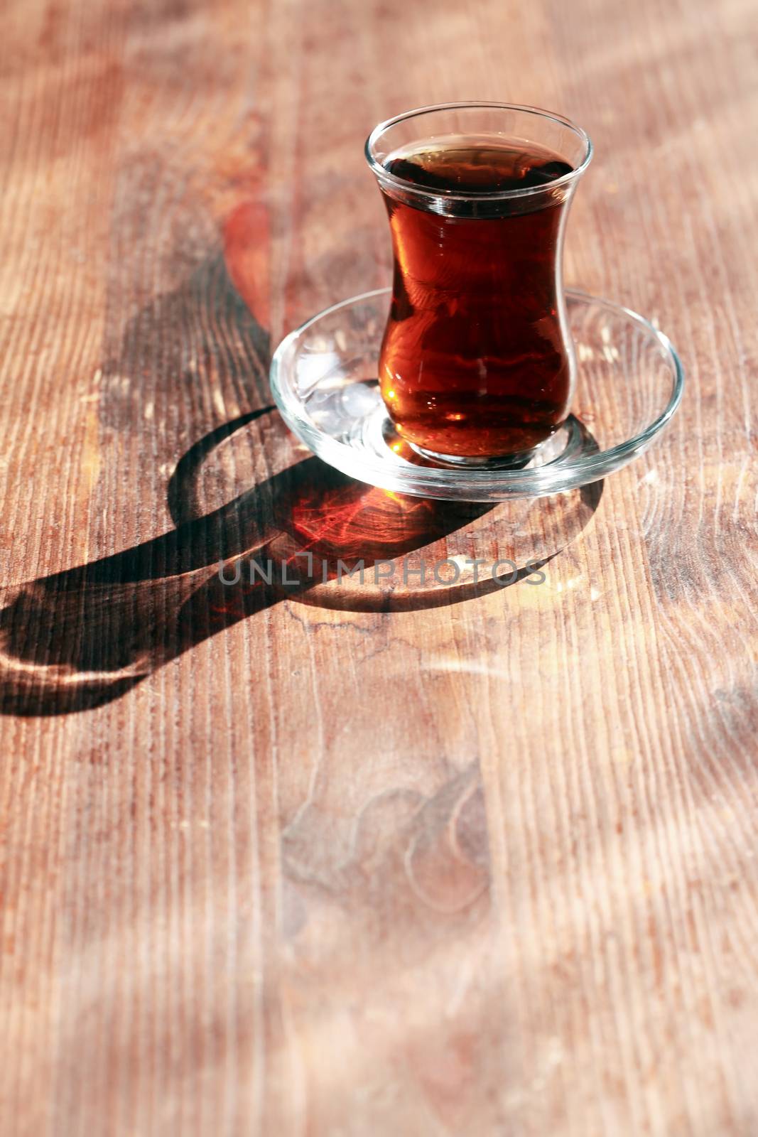 Cup of Turkish tea on wooden table under sunlight