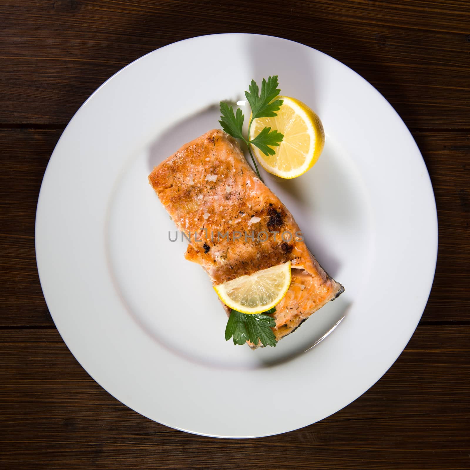 High Angle View Of Grilled Salmon In Plate with lemon and parsley