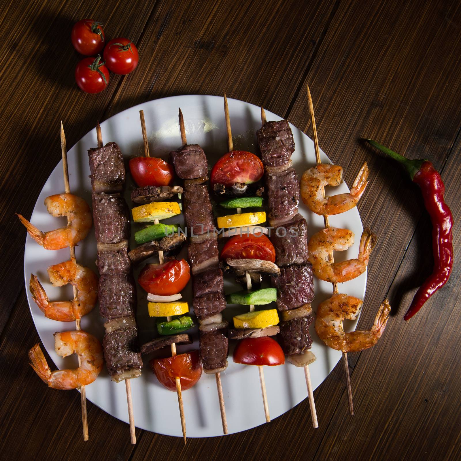 Skewered meat, shrimp and vegetables on a plate, Studio shoot