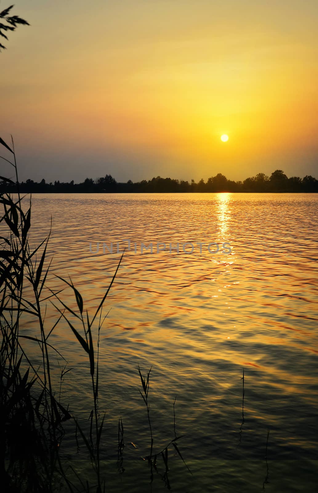 Landscape with sunset over the lake with the reflection of light on the surface of the water