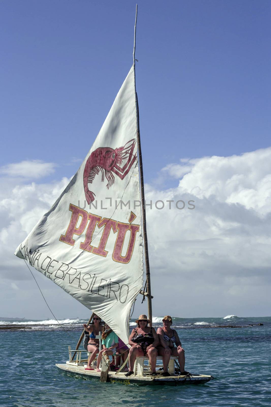 Pernambuco, Brazil July 6, 2016: An unidentified group of people in Chicken Beach with typical sail boats in Ipojuca City near barrier reef, northeast Brazil