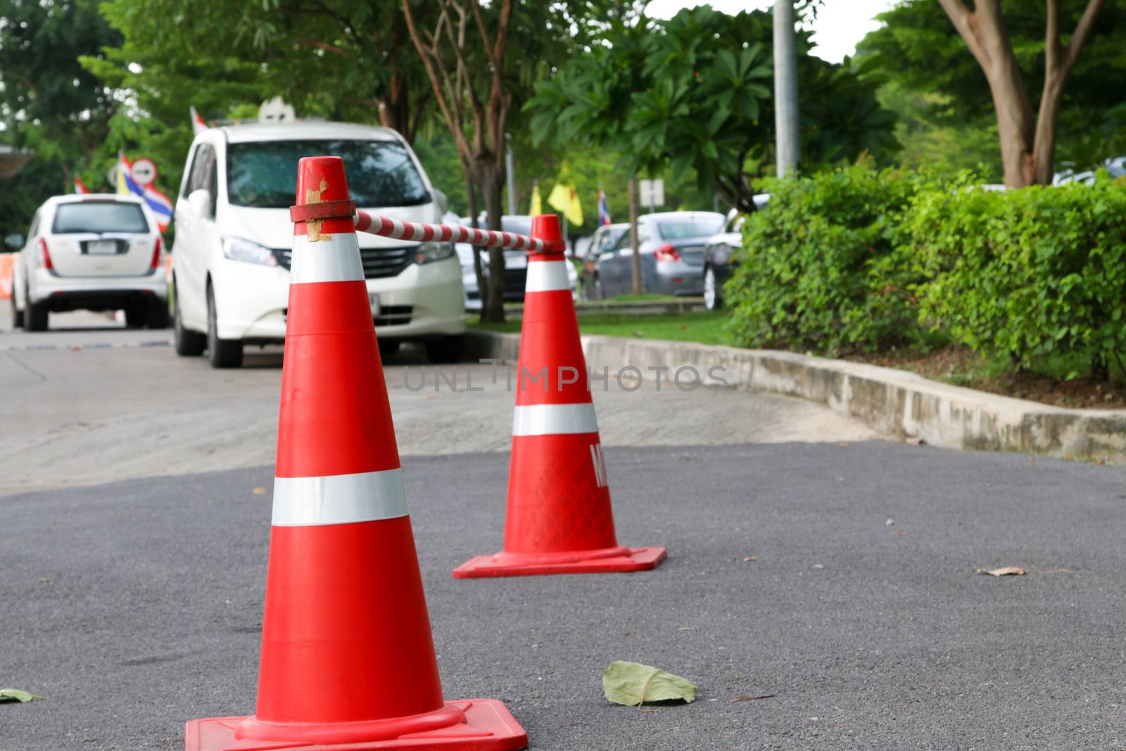 traffic cone, with white and orange stripes on gray asphalt,