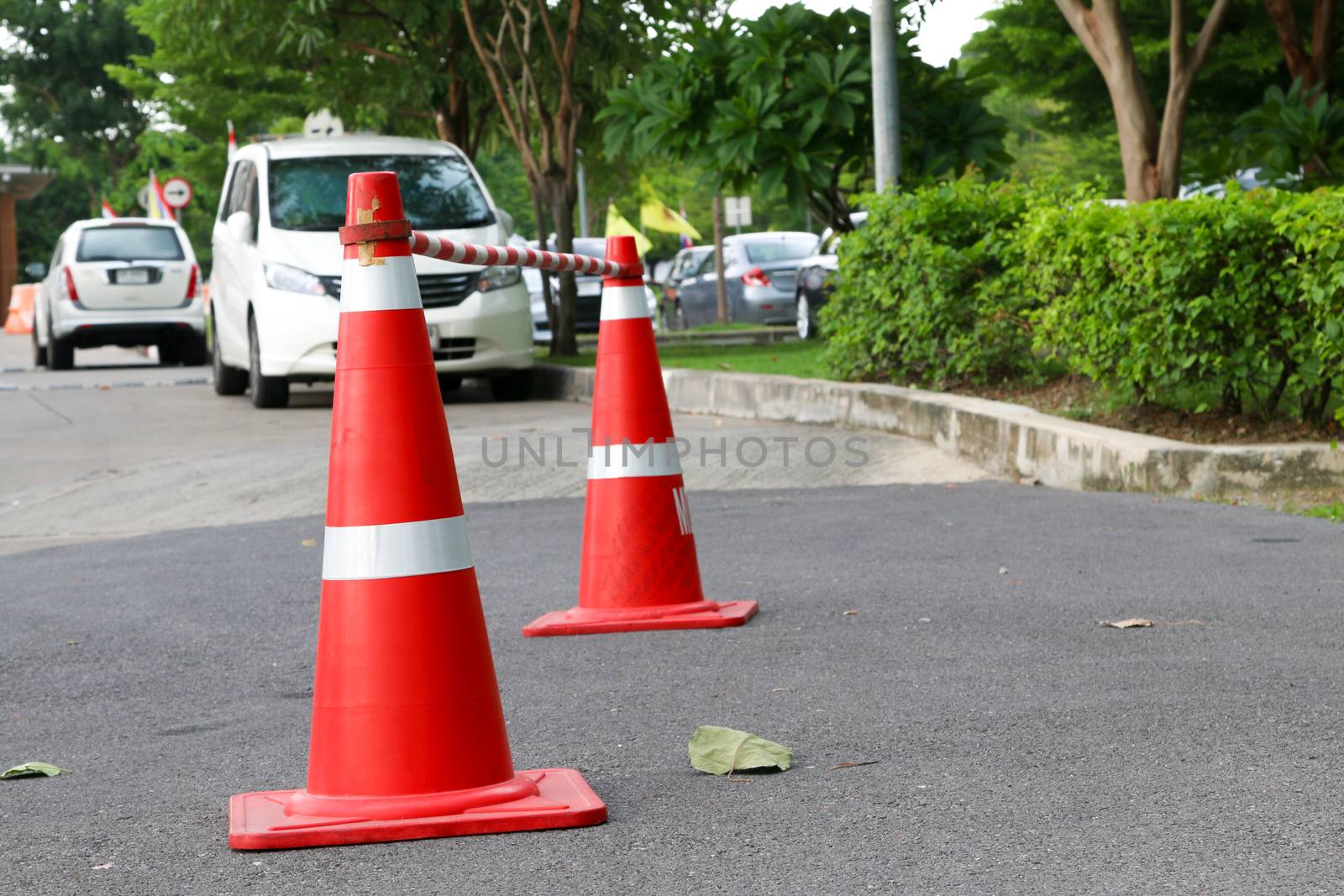 traffic cone, with white and orange stripes on gray asphalt,