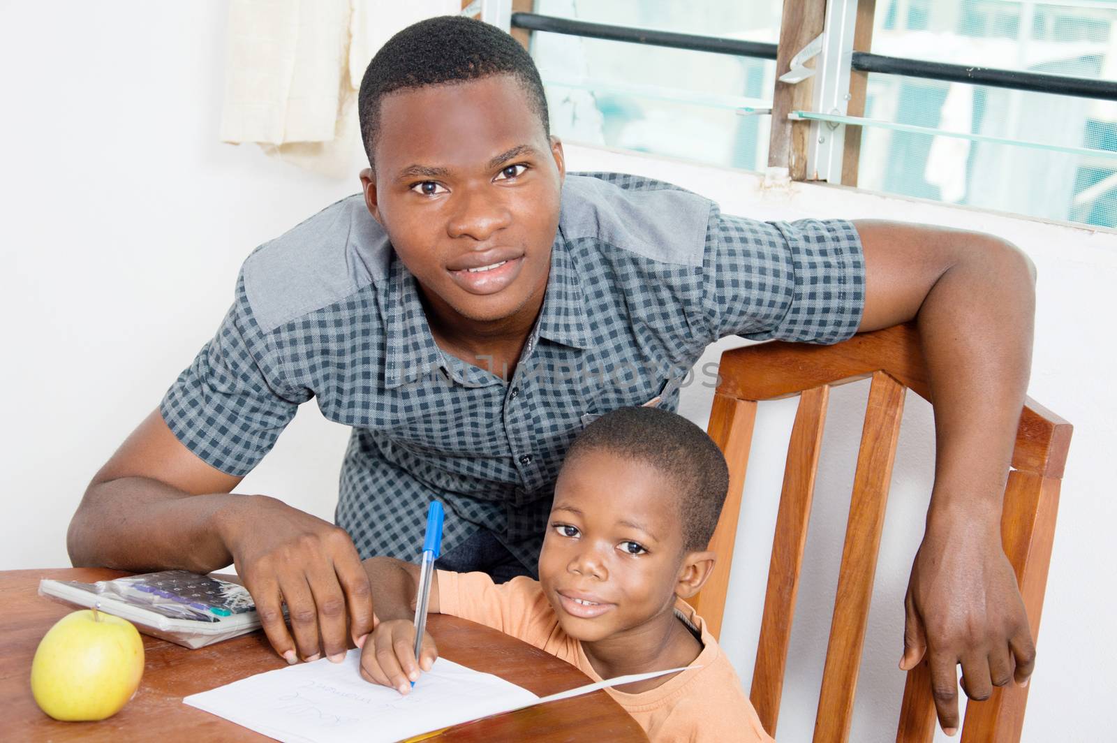 The child and his teacher watch the camera for a shoot.