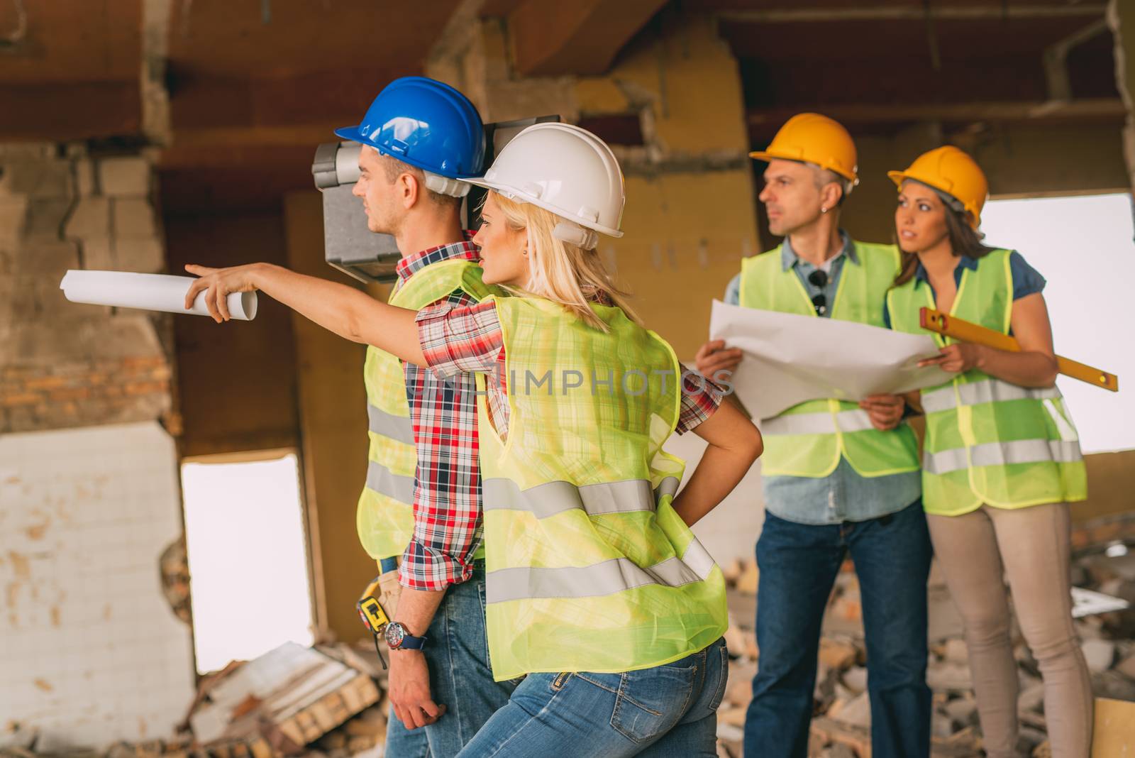 Four construction architects review plan in front building damaged in the disaster. Selective focus.