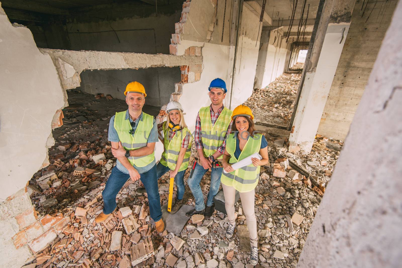 Four construction architects in building damaged in the disaster. Looking at camera.