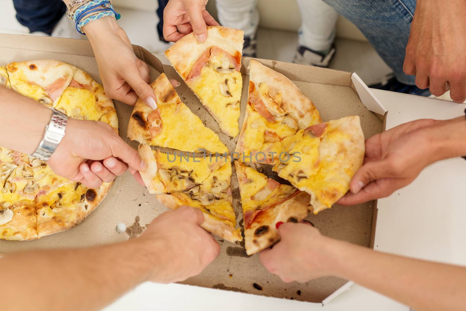 Cropped shot of a group of friends taking pizza slices together.